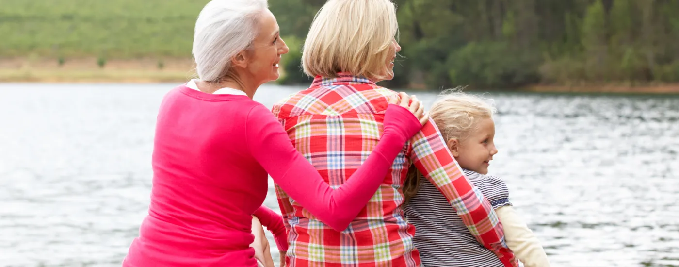three generations of females sitting by a lake
