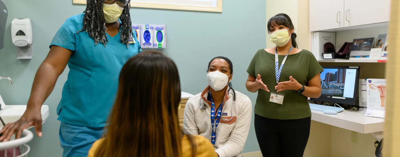 OB-GYN staff speaks with a patient in an exam room