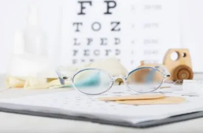 Glasses on a notepad with a sight chart in the background