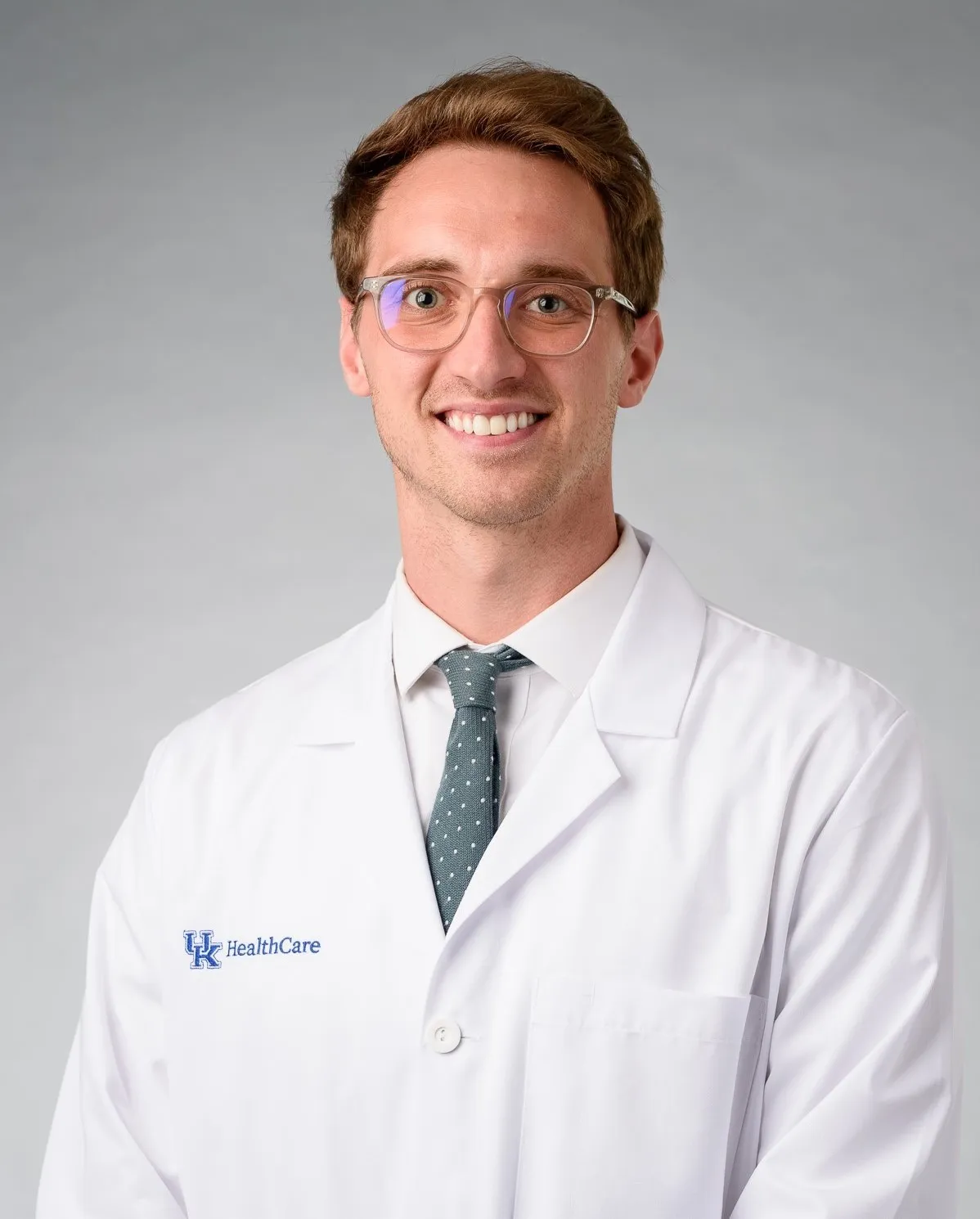 Justin Gillette posing in white coat