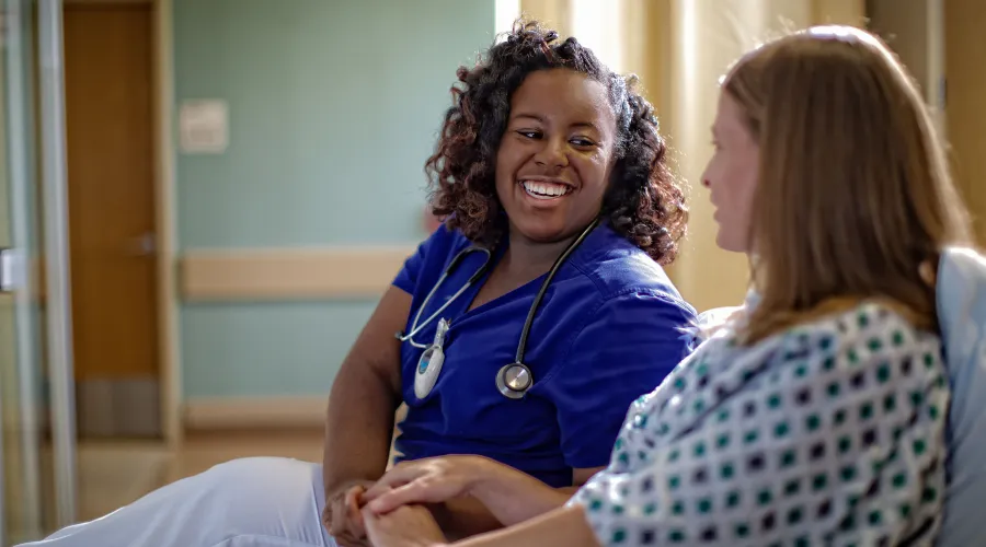 provider sitting beside patient in hospital bed